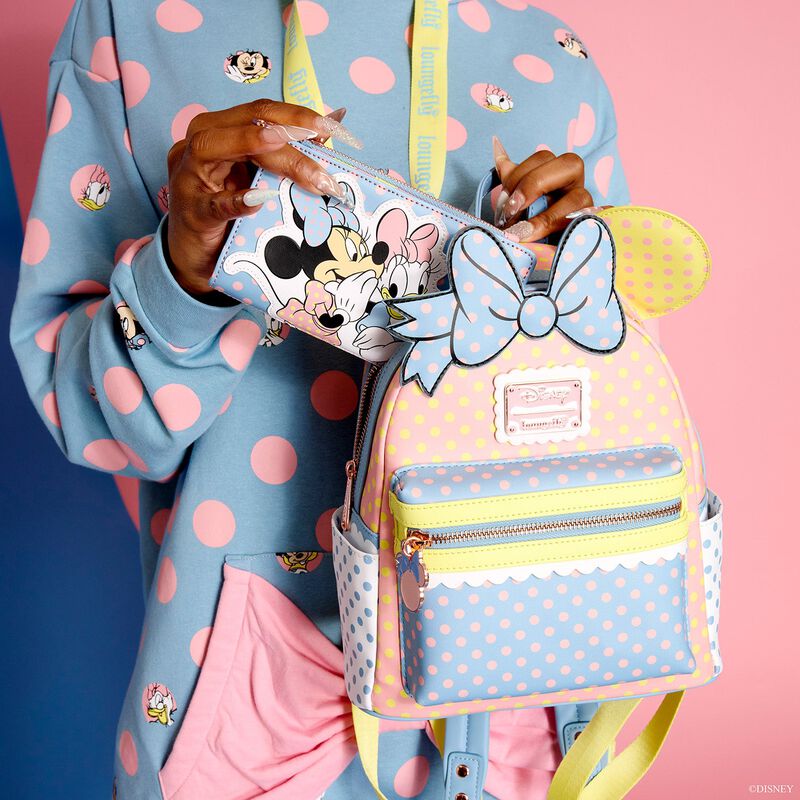 Woman holding the Minnie Mouse Pastel Polka Dot Backpack, which has a pastel color scheme and color block style of pink, blue, yellow, and white